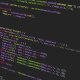 JavaScript code displayed on a dark monitor, showing colorful syntax highlighting.