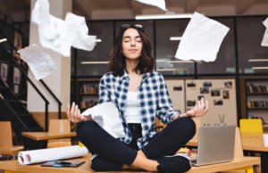 Woman meditating at a desk while papers float around her, symbolizing stress-free document management.