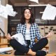 Woman meditating at a desk while papers float around her, symbolizing stress-free document management.